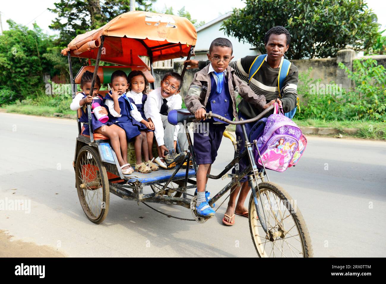Madagassische Grundschulkinder, die in einer Radfahrrikscha in Moramanga, Madagaskar, zur Schule gehen. Stockfoto