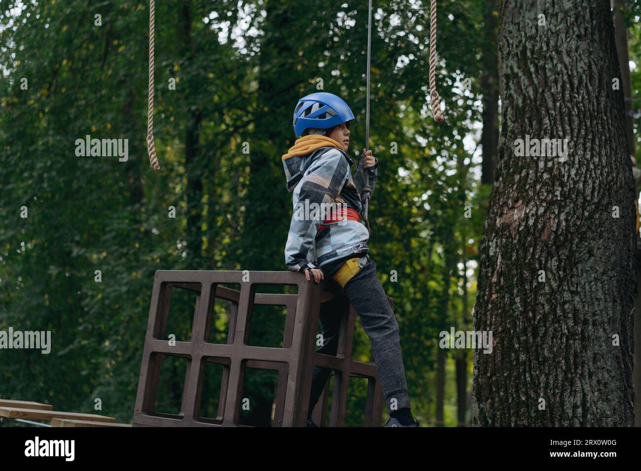 Teenager-Boyin Outdoor-Abenteuerpark, der Hindernisparcours passiert. Hochseilpark. Hochwertige Fotos Stockfoto