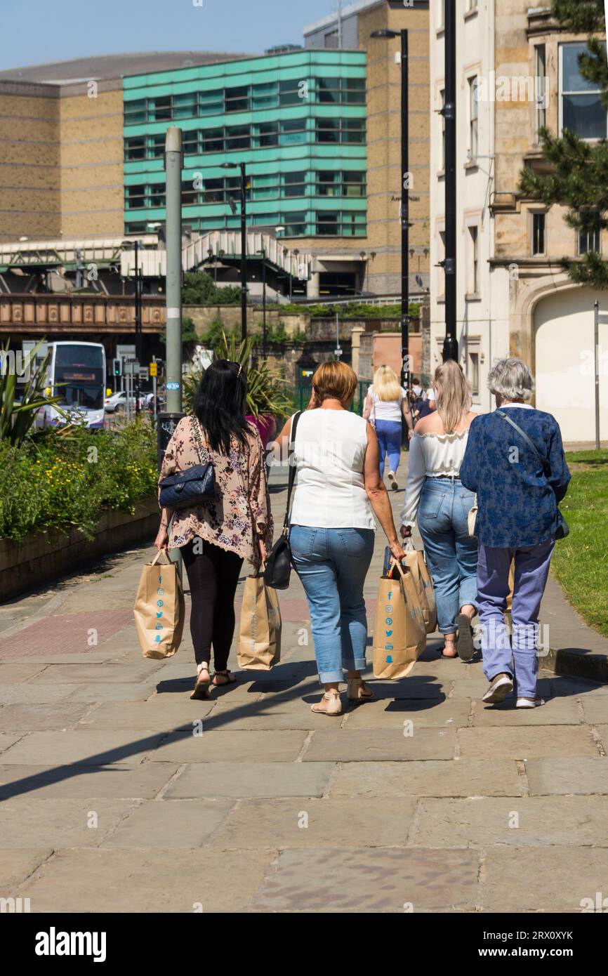 Gruppe von vier Frauen, die in Manchester einkaufen und große Primark-Tragetaschen in der Victoria Street tragen. Stockfoto
