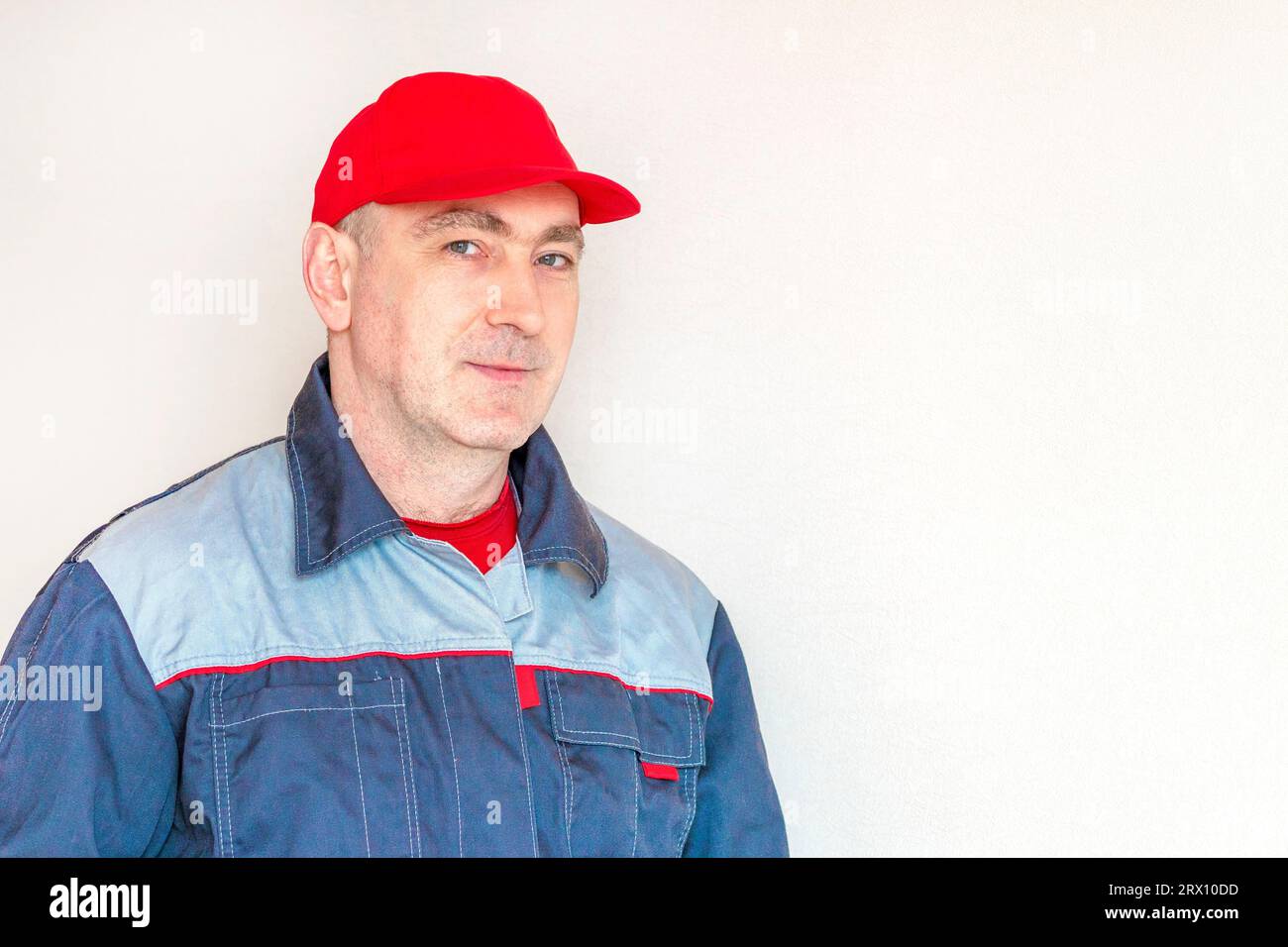 Mann mit Mütze und Arbeitskleidung. Arbeitender Mann, Profi, Vorarbeiter. Konzept persönliche Schutzausrüstung. Kopierraum Stockfoto