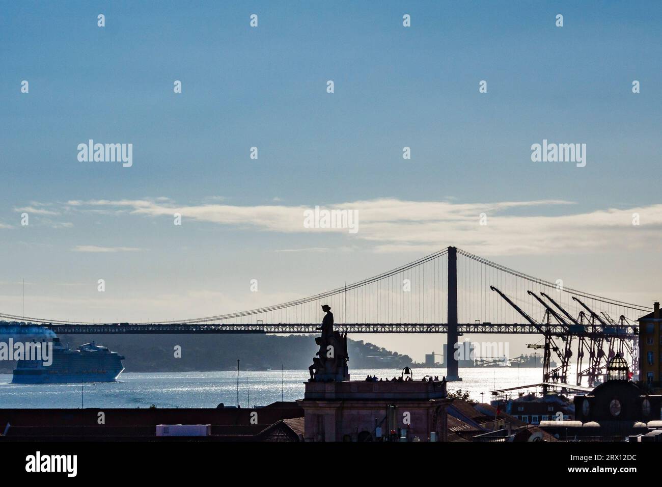 Ein Blick auf Lissabons 25 de Abril Brücke über den Fluss Tejo, mit dem riesigen Rua Augusta Arch (Arco do Triunfo) in der Mitte des Bildes Stockfoto