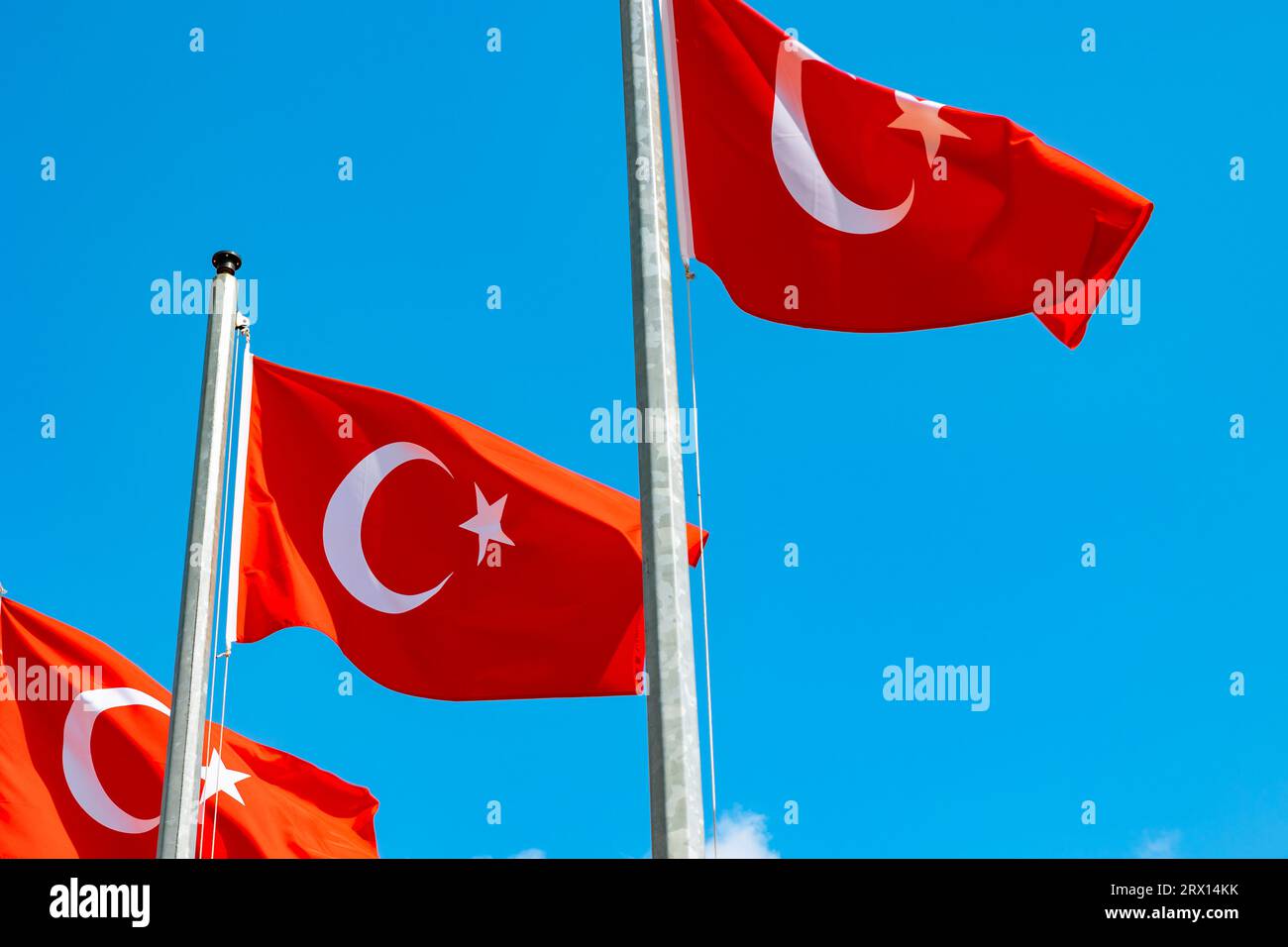 Drei türkische Flaggen winken auf dem Fahnenmast isoliert auf blauem Himmel Hintergrund. Hintergrundfoto der türkischen Nationalfeiertage. Stockfoto