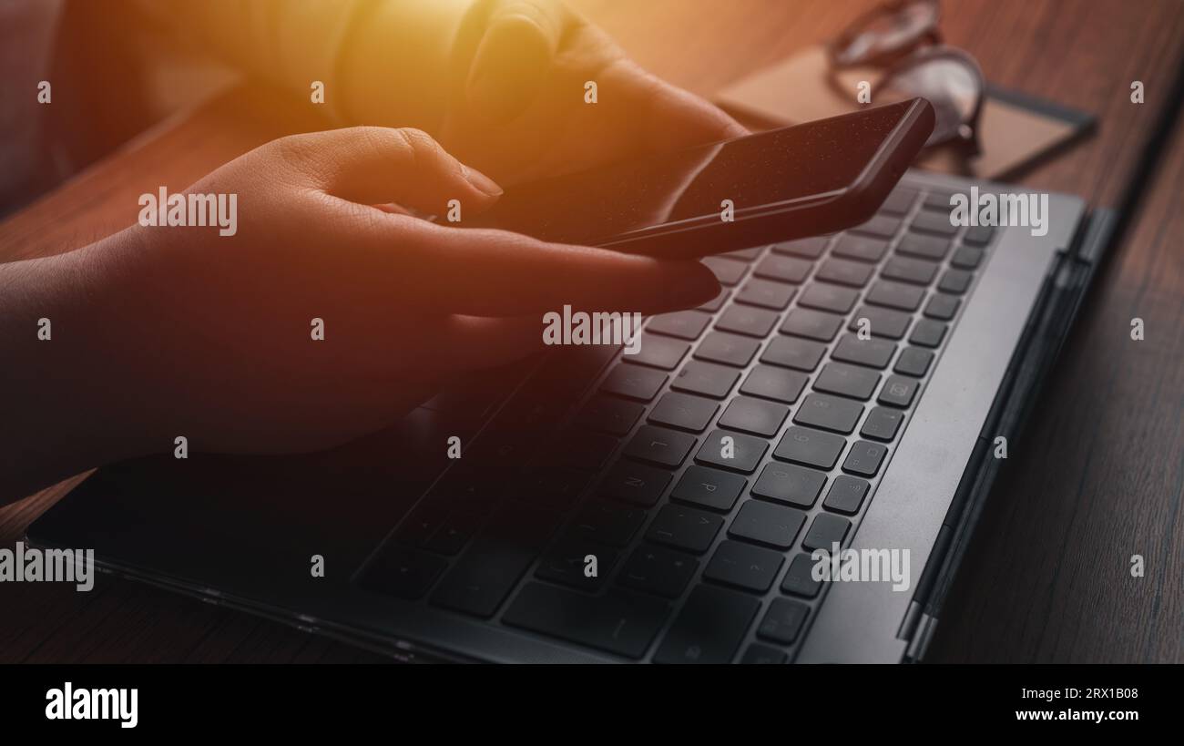 Geschäftsfrau, die am Schreibtisch mit Smartphone und Laptop arbeitet. Stockfoto