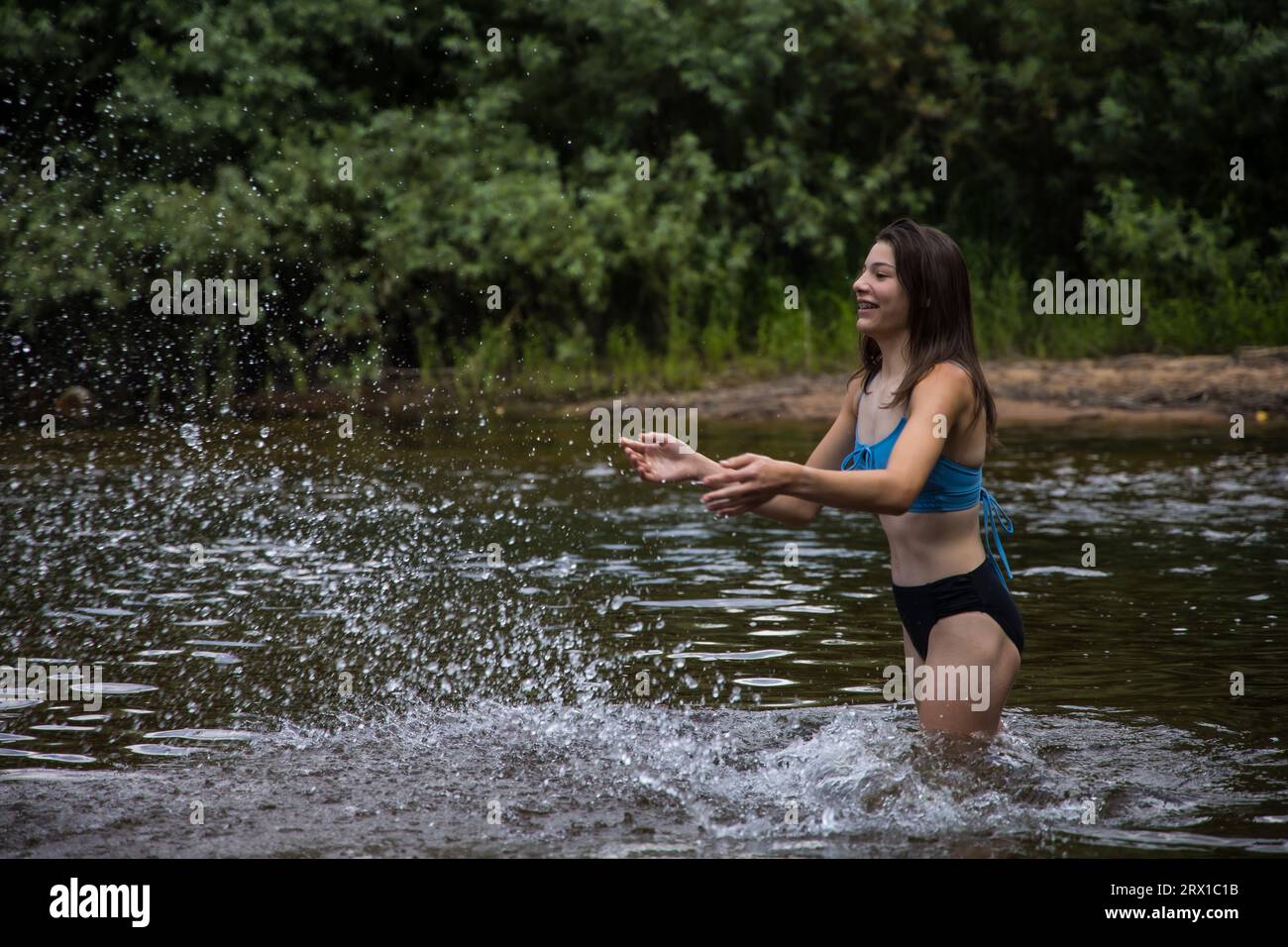 Teenager-Mädchen, das Wasser in einen Fluss spritzt Stockfoto