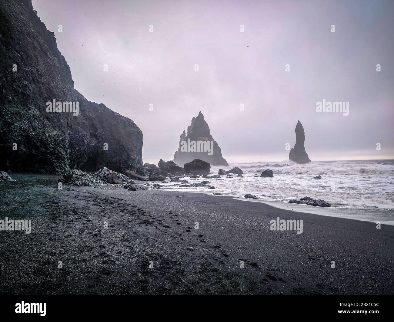 Schwarzer Sandstrand mit Felsformationen im Hintergrund Stockfoto