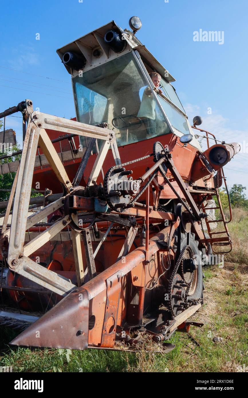 Ein kleiner Junge spielt auf einem alten Erntemaschine Stockfoto