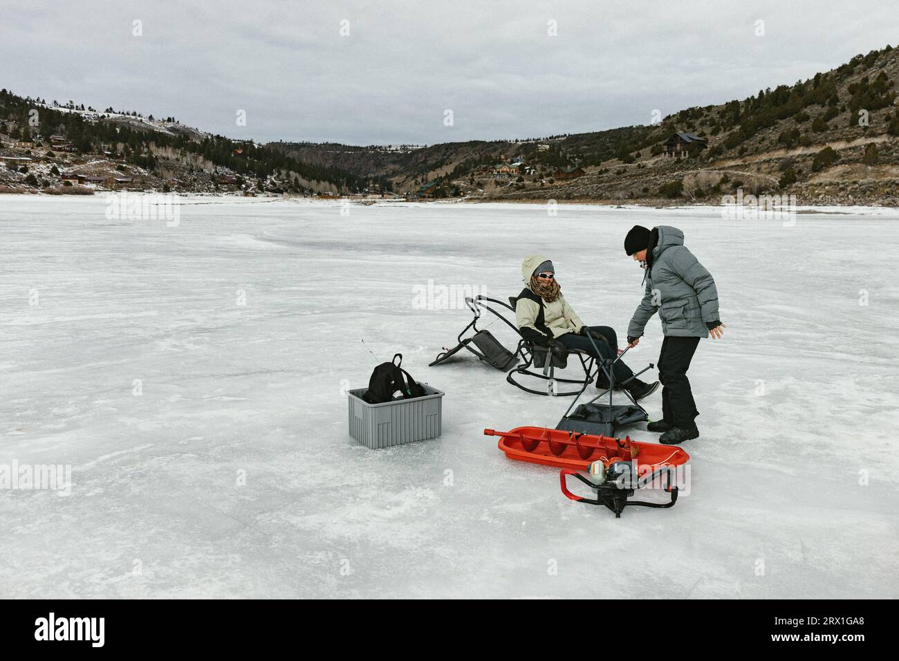 Familie auf gefrorenem See im Winter mit Schlitten und Eisangeln Werkzeuge Stockfoto