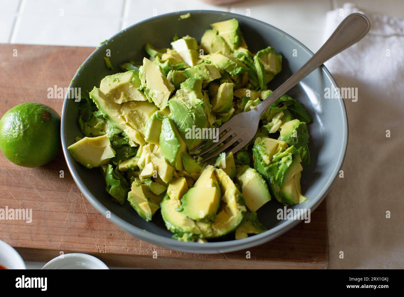 Graue Schüssel voller gehackter Avacado auf dem Schneidebrett Stockfoto