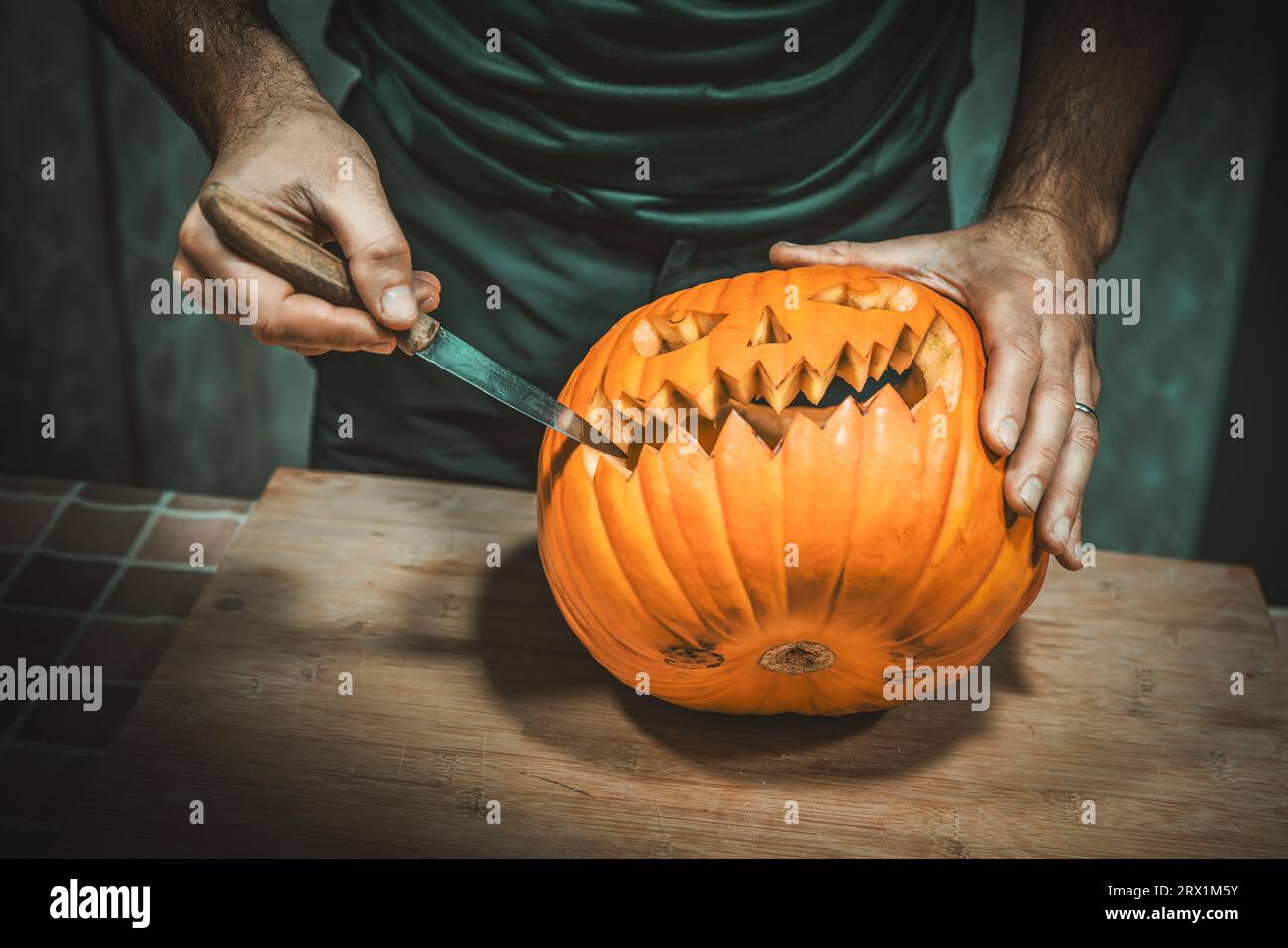 Der Mann schnitzt einen halloween-Kürbis mit einem Messer Stockfoto