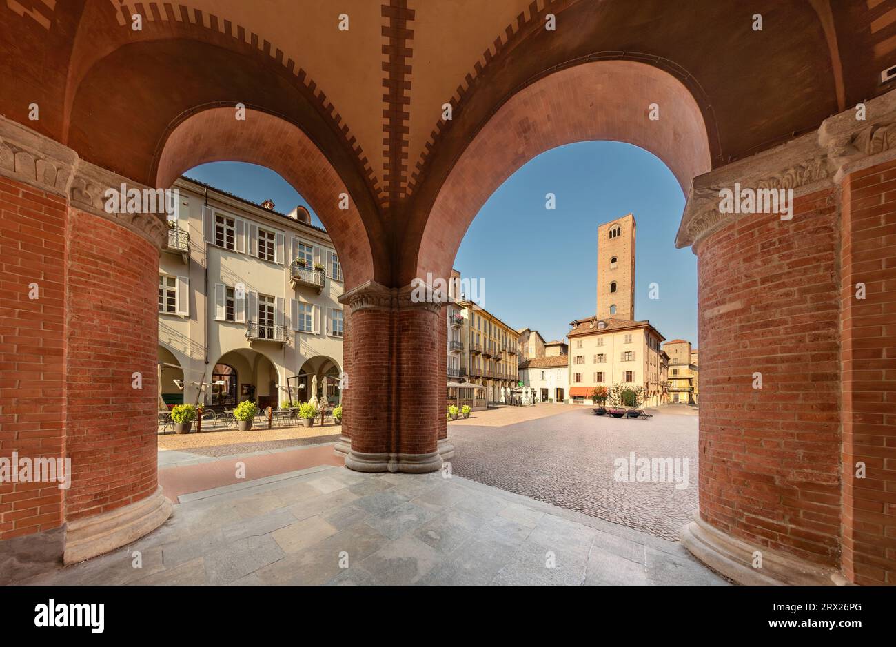 Alba, Langhe, Piemont, Italien - 20. August 2023: Piazza Risorgimento, historisches Stadtzentrum mit mittelalterlichem Turm, von den Arkaden der Kathedrale aus gesehen Stockfoto