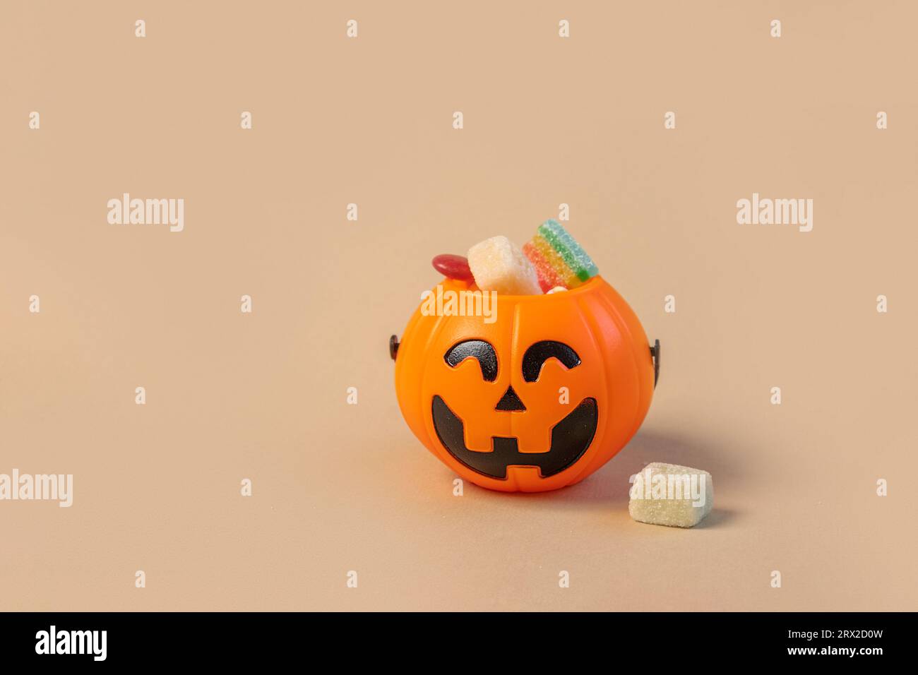 Halloween Jelly Beans. Happy Halloween Party Border Beige Hintergrund. Banner Für Ästhetisches Zubehör. Gruseliger Orangener Kürbis-Süßigkeiteneimer. Moderner Urlaub Stockfoto