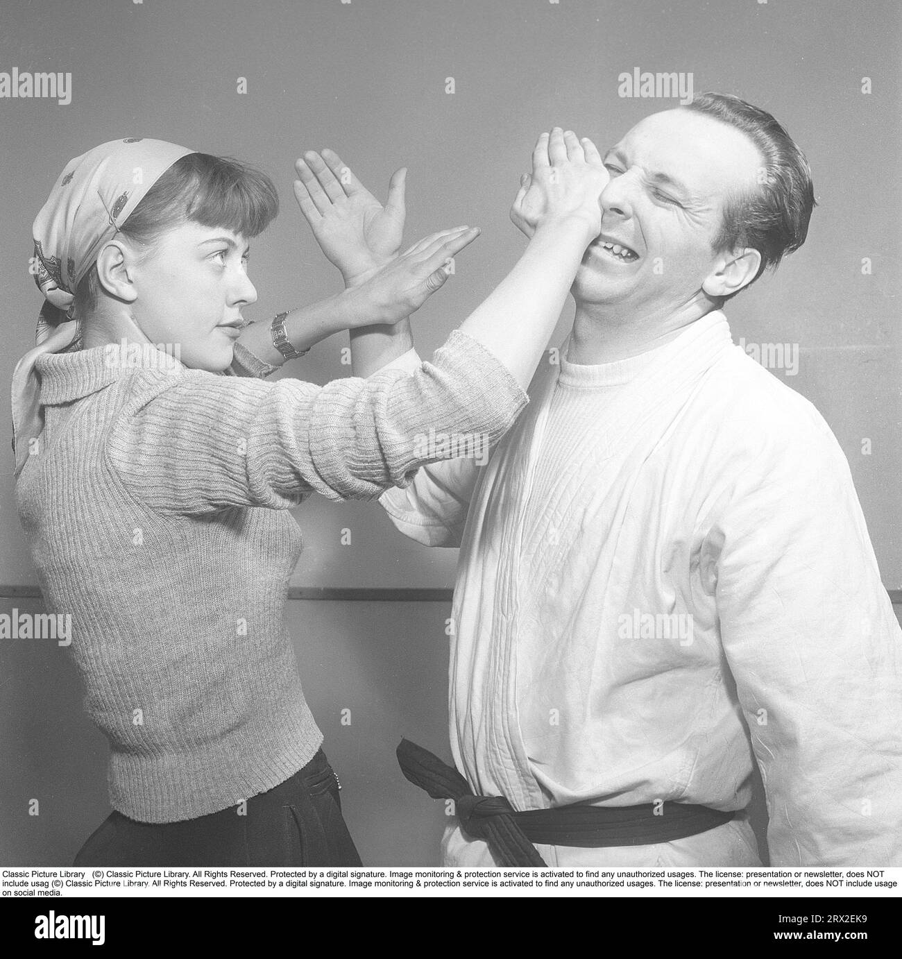 In den 1950er Jahren Eine junge Frau, die an einem Selbstverteidigungskurs teilnimmt und den Teatcher überrascht, da er schnell lernt, verteidigt sie sich mit ihrer linken Hand und bekommt einen guten Schlag auf sein Gesicht und die Nase, wobei er sichtlich Schmerzen hat. Schweden 1951. Foto Kristoffersson Ref. BD37-3 Stockfoto