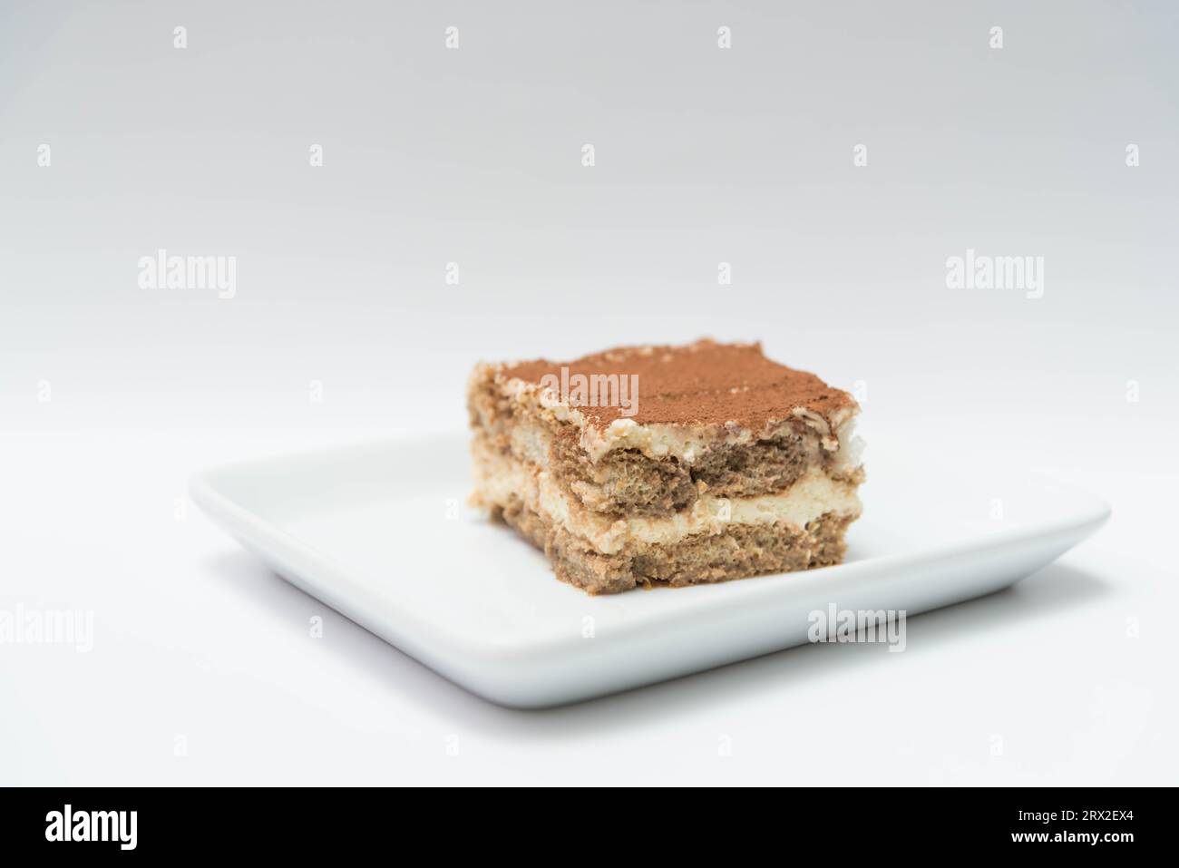 Ein Würfel/quadratischer Block Tiramisu, serviert auf einem weißen Teller Stockfoto