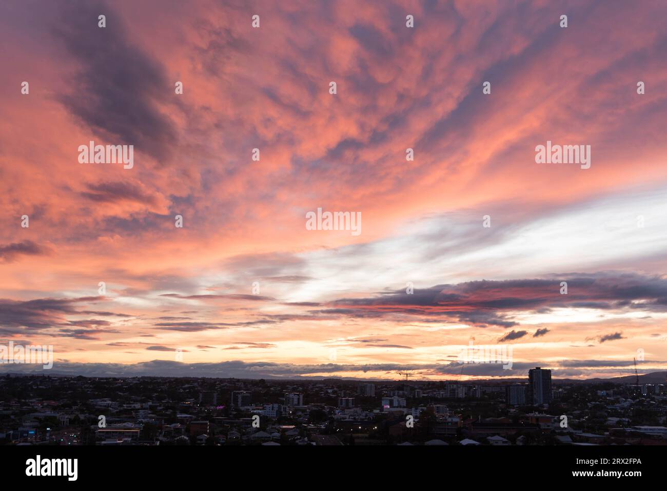 Orangefarbener lila Sonnenuntergang am Himmel mit der Skyline von Brisbane Stockfoto