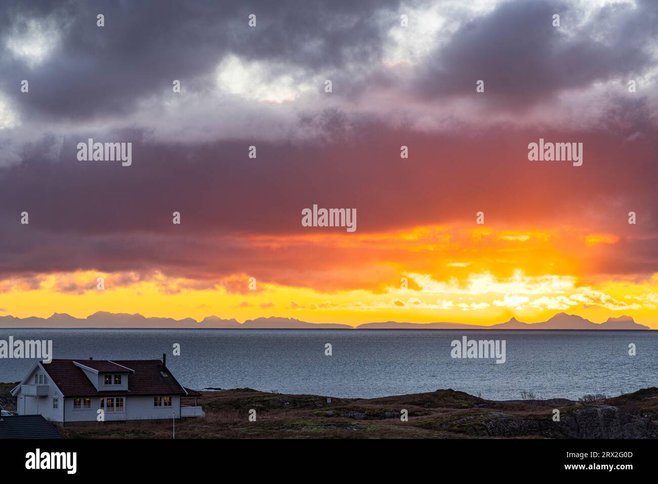 Einsames traditionelles Haus am Meer unter einem dramatischen Himmel bei Sonnenaufgang, reine, Lofoten-Inseln, Nordland, Norwegen, Skandinavien, Europa Stockfoto