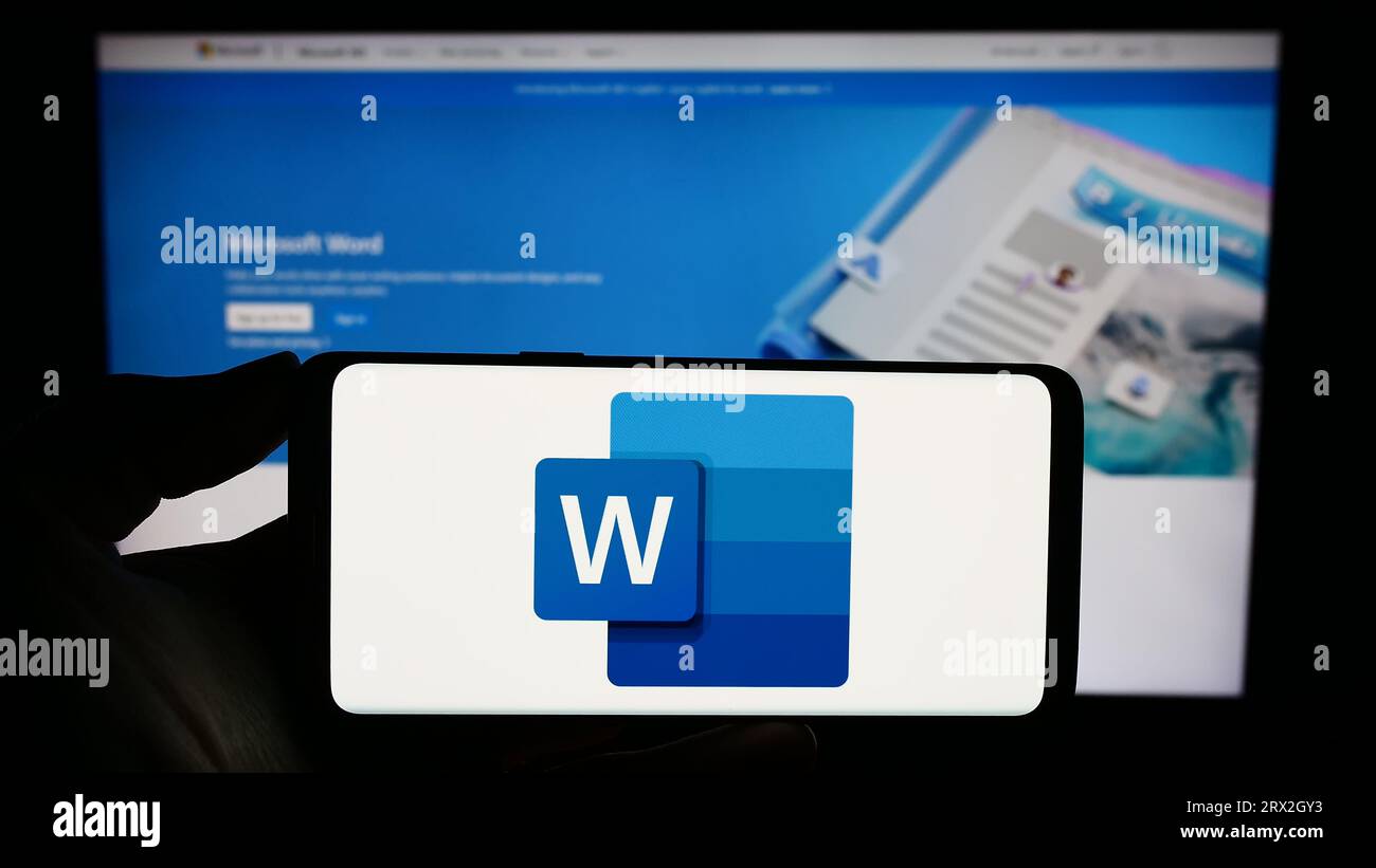 Person, die ein Smartphone mit dem Logo der Textverarbeitungssoftware Microsoft Word auf dem Bildschirm vor der Website hält. Konzentrieren Sie sich auf das Display des Telefons. Stockfoto