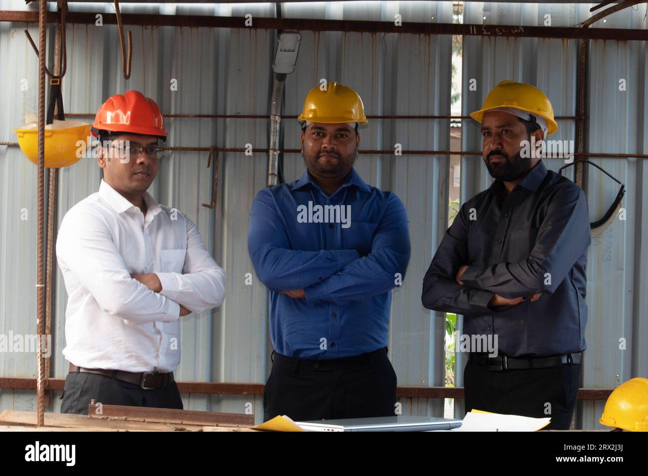 Porträt des männlichen Ingenieurteams auf der Baustelle. Erfahrene, selbstbewusste Architekten mit gekreuzten Armen. Rat Für Entwicklung Der Bauindustrie Stockfoto