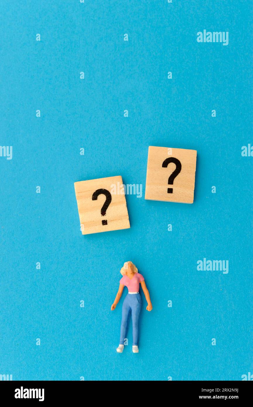 Miniaturfigur der Frau, Fragezeichen und Ausrufezeichen Stockfoto