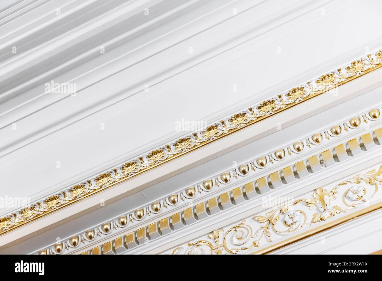 Weiße Deckenrelief-Dekoration mit goldfarbenen klassischen Designelementen. Abstrakte Architekturdetails Stockfoto