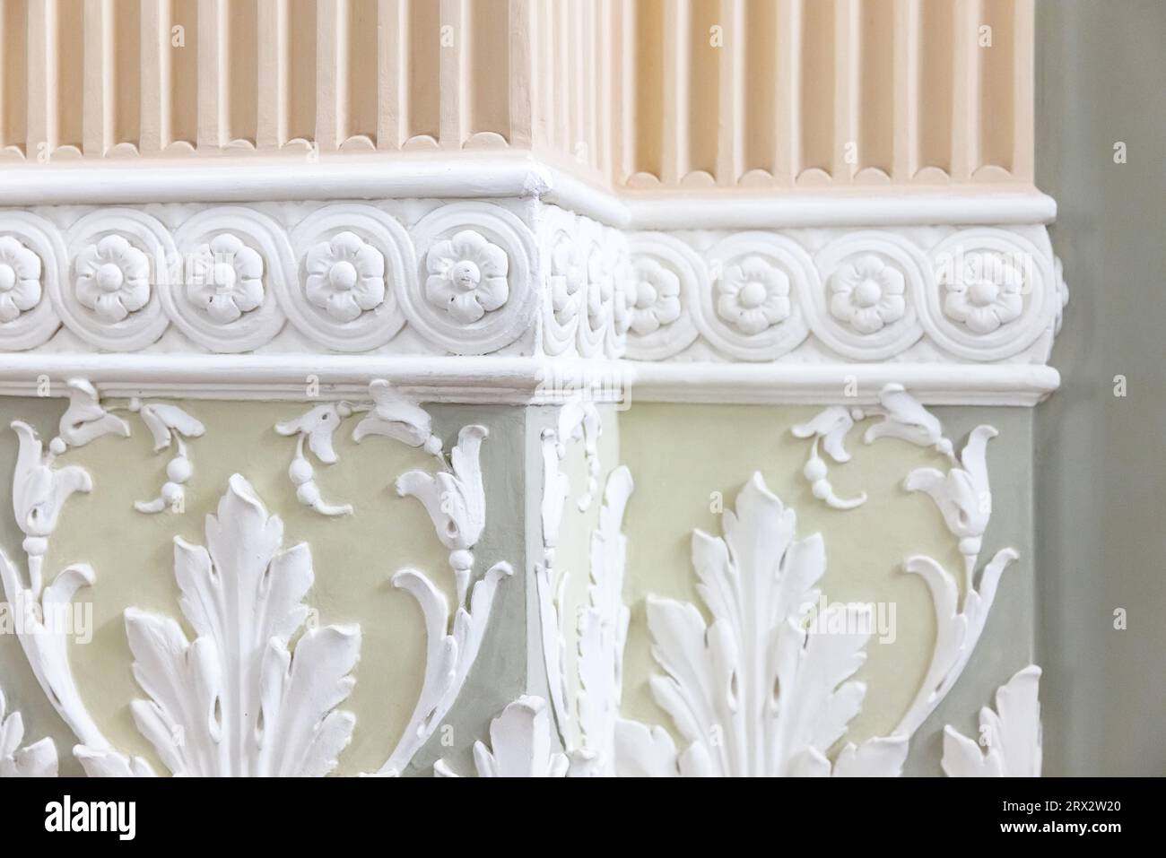 Hellgrüne Wand mit Säulen, die mit klassischer Stuckdekoration bedeckt sind, abstraktes Innenfragment mit Blumenornamenten Stockfoto