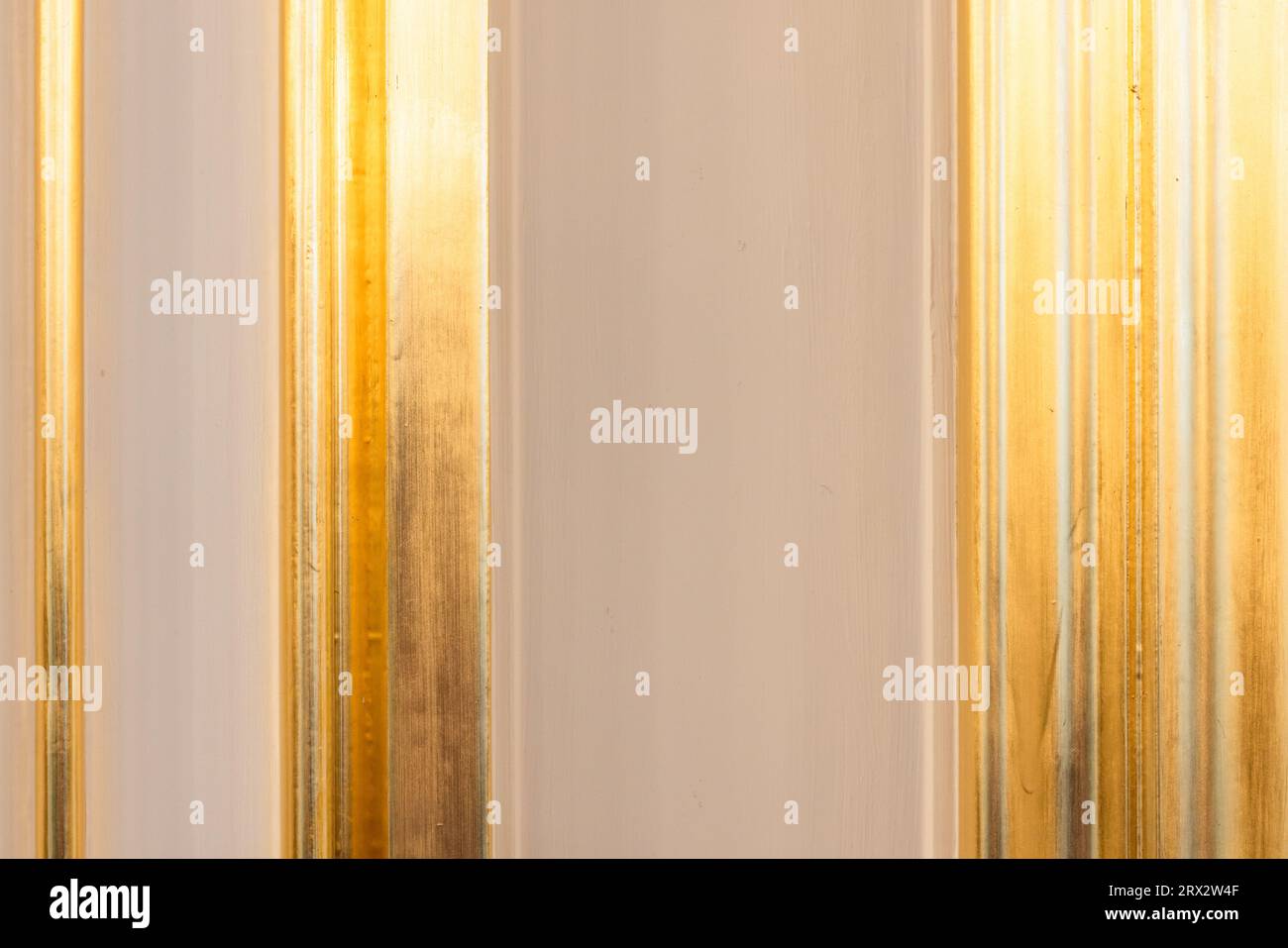 Geformte Wanddekoration mit vertikalen goldfarbenen Elementen, klassischer Hintergrund für die Inneneinrichtung Stockfoto