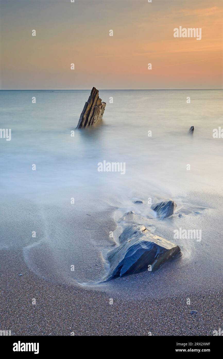 Surf rollt bei Sonnenuntergang um die Küstenfelsen in Ayrmer Cove, einer abgelegenen Bucht in der Nähe von Kingsbridge, Südküste von Devon, England, Großbritannien, Europa Stockfoto