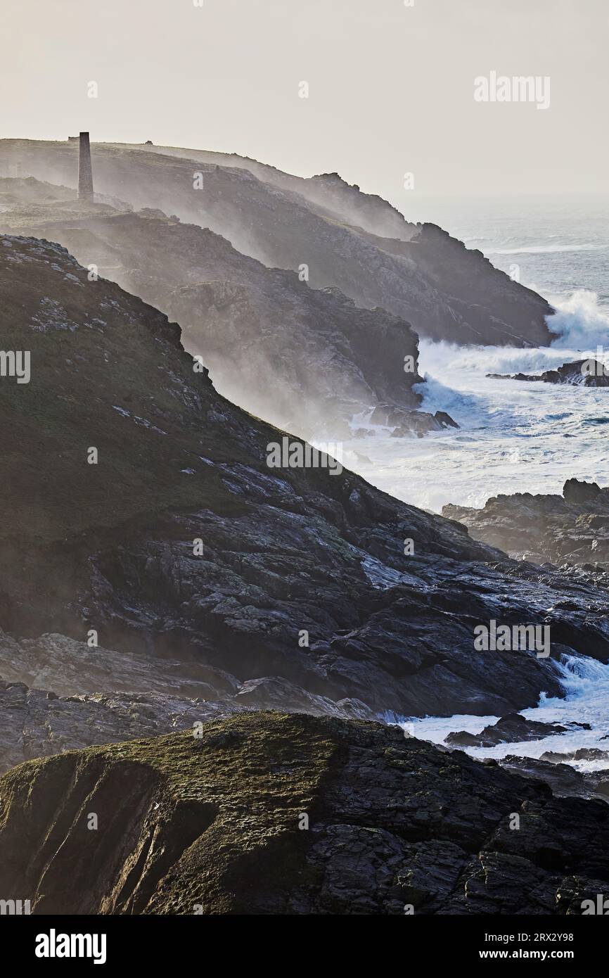 Bei stürmischem Winterwetter werden die Klippen des Atlantiks in Pendeen von der Brandung durchbrochen, mit den Ruinen alter Zinnminen Stockfoto