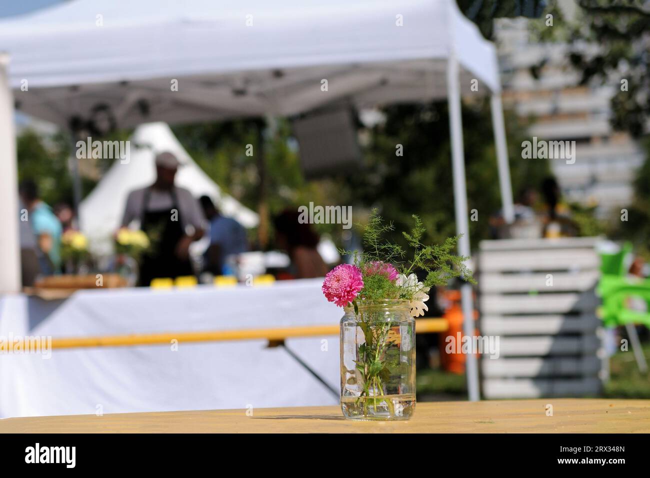 Blumendekoration mit einem verschwommenen Verkaufszelt im Hintergrund bei einem Lebensmittelfestival im Sommer Stockfoto