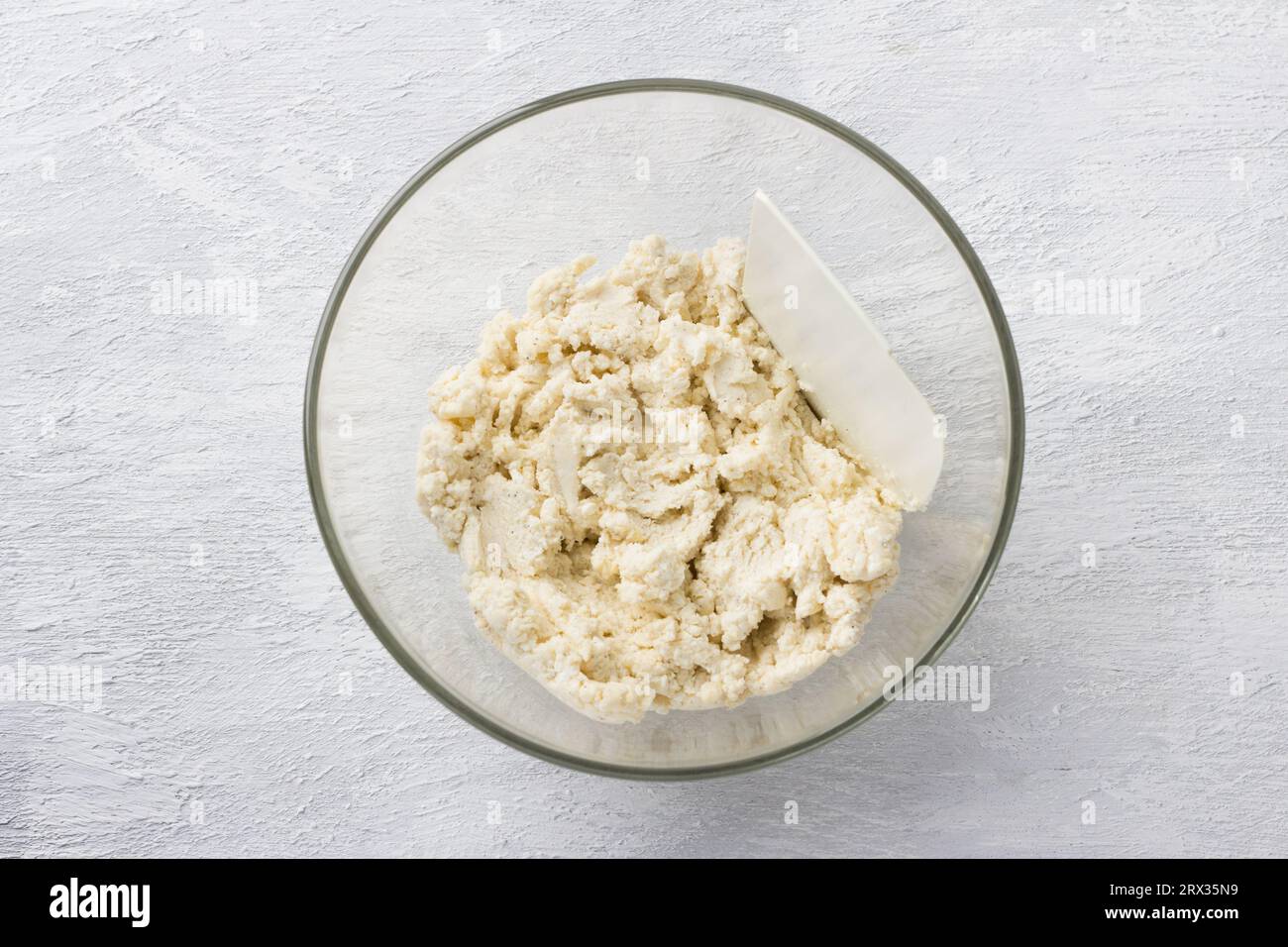 Glasschale mit Teig für gebackene Hüttenkäse-Gnocchi auf hellgrauem Hintergrund, Draufsicht. Kochbühne. Stockfoto