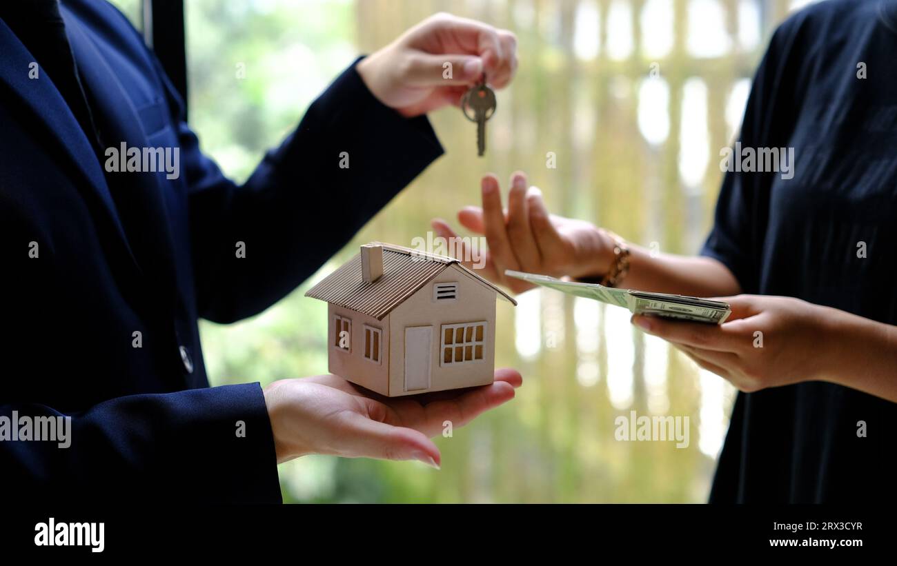 Männlicher Geschäftsmann oder Immobilienmakler, der den Hausschlüssel für seinen Kunden hält, nachdem er den Vertrag im Amt unterzeichnet hat. Stockfoto