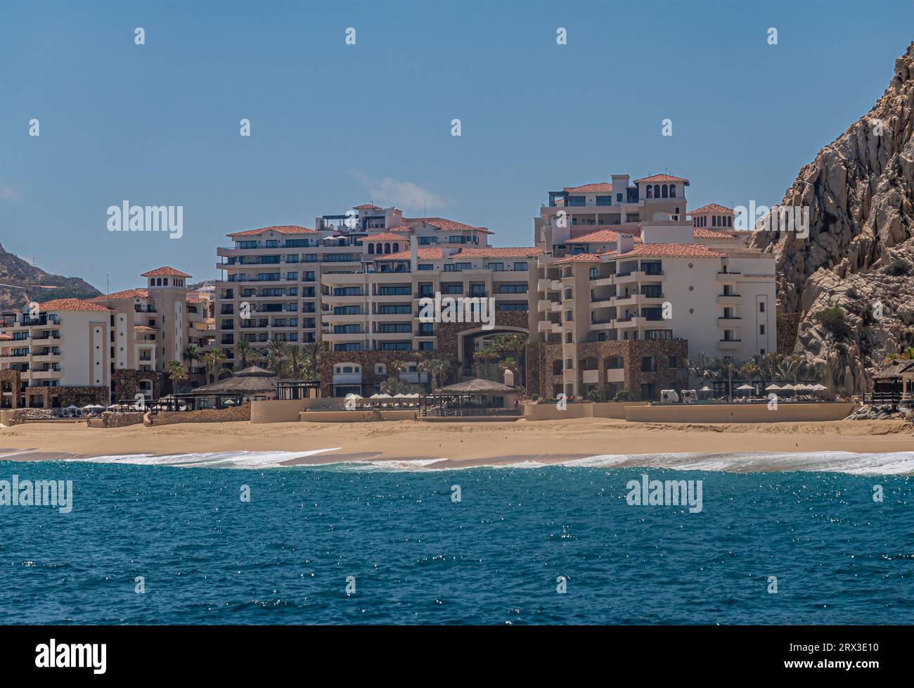Mexiko, Cabo San Lucas - 16. Juli 2023: Grand Solmar Lands End Resort und Spa-Gebäude hinter Sandstrand und Surfen von blauem Wasser unter blauem Himmel Stockfoto