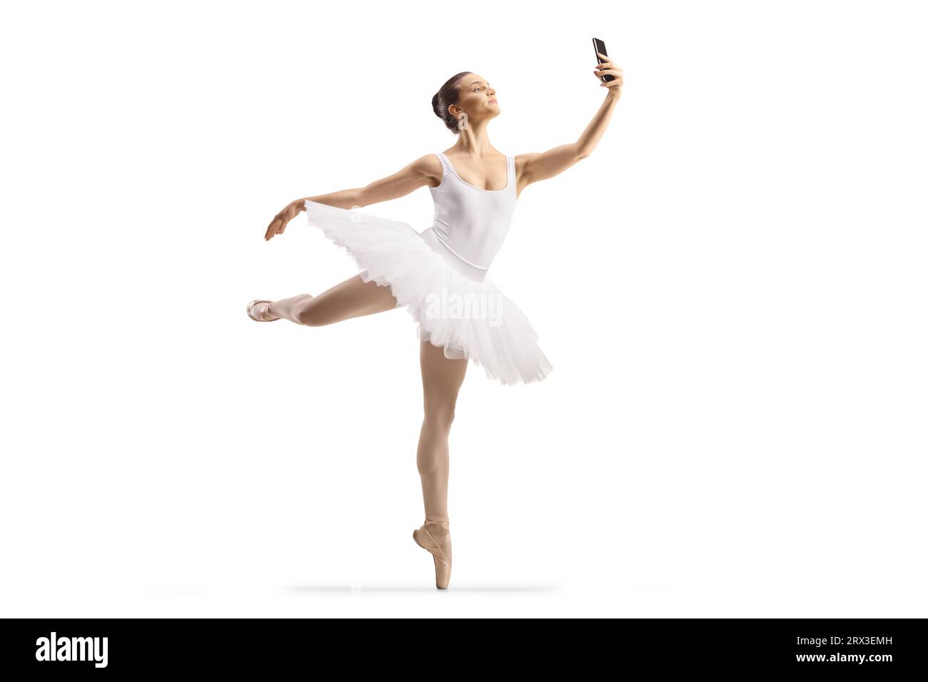 Aufnahme einer Ballerina in voller Länge, die tanzt und ein Smartphone auf weißem Hintergrund verwendet Stockfoto