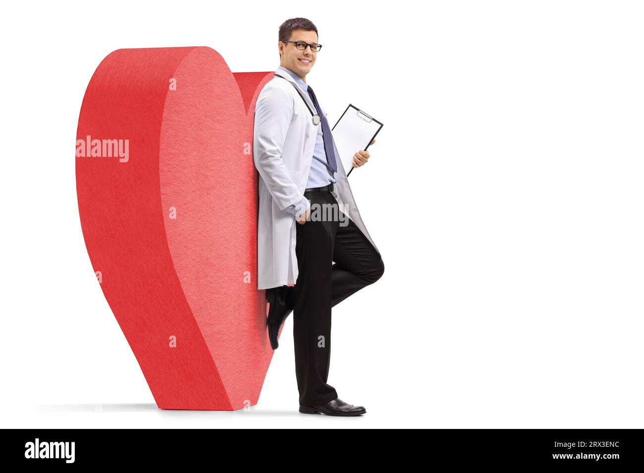 Junger männlicher Kardiologen-Arzt, der sich auf ein großes rotes Herz stützt, isoliert auf weißem Hintergrund Stockfoto
