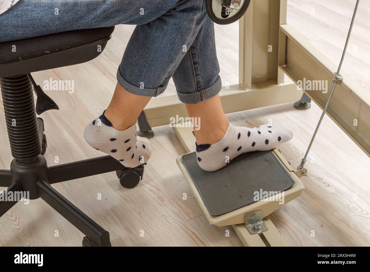 Weibliche Füße auf dem Pedal einer Nähmaschine, Nahaufnahme des Motors Stockfoto