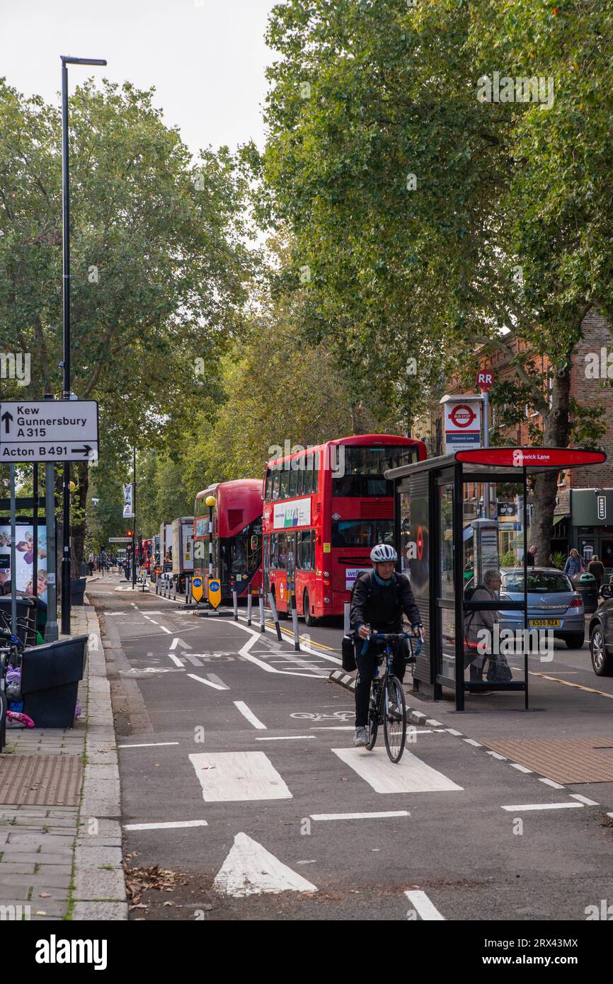 London, Großbritannien. September 2023. Einzelradfahrer in Chiswicks umstrittenem Permanent C9 Cycle Lane, der kürzlich vom Hounslow Council dauerhaft gemacht wurde, trotz heftiger Opposition vieler Einwohner von Chiswick und aller seiner lokalen Konkilloren. Einsame Radfahrer fahren auf der bidirektionalen Spur in Richtung Hammersmith, während viele Buspassagiere im Westverkehr anstehen. Quelle: Peter Hogan/Alamy Live News Stockfoto