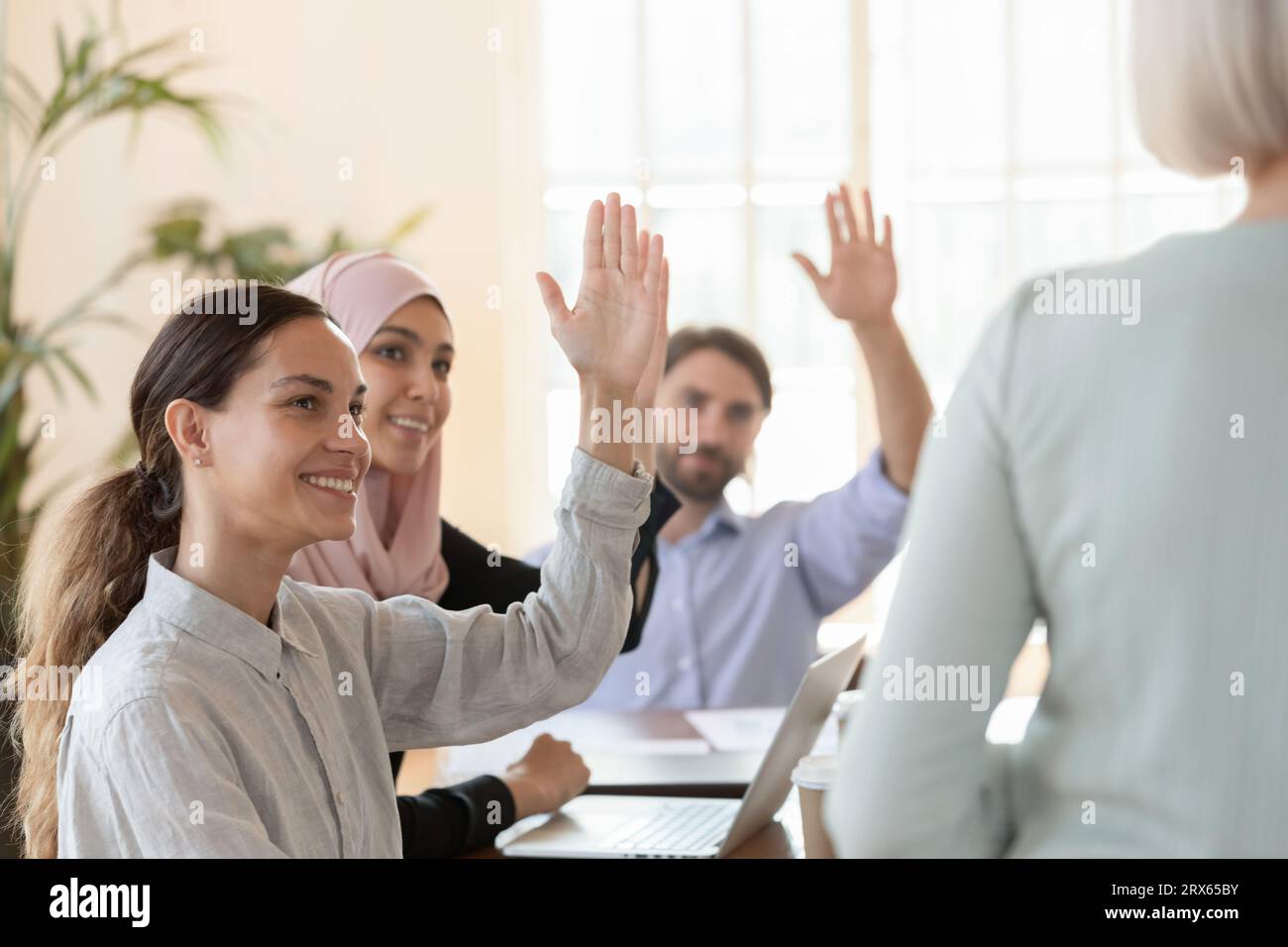 Multikulturelle Mitarbeiter erheben bei Gruppenbesprechungen einstimmig ihre Stimme Stockfoto