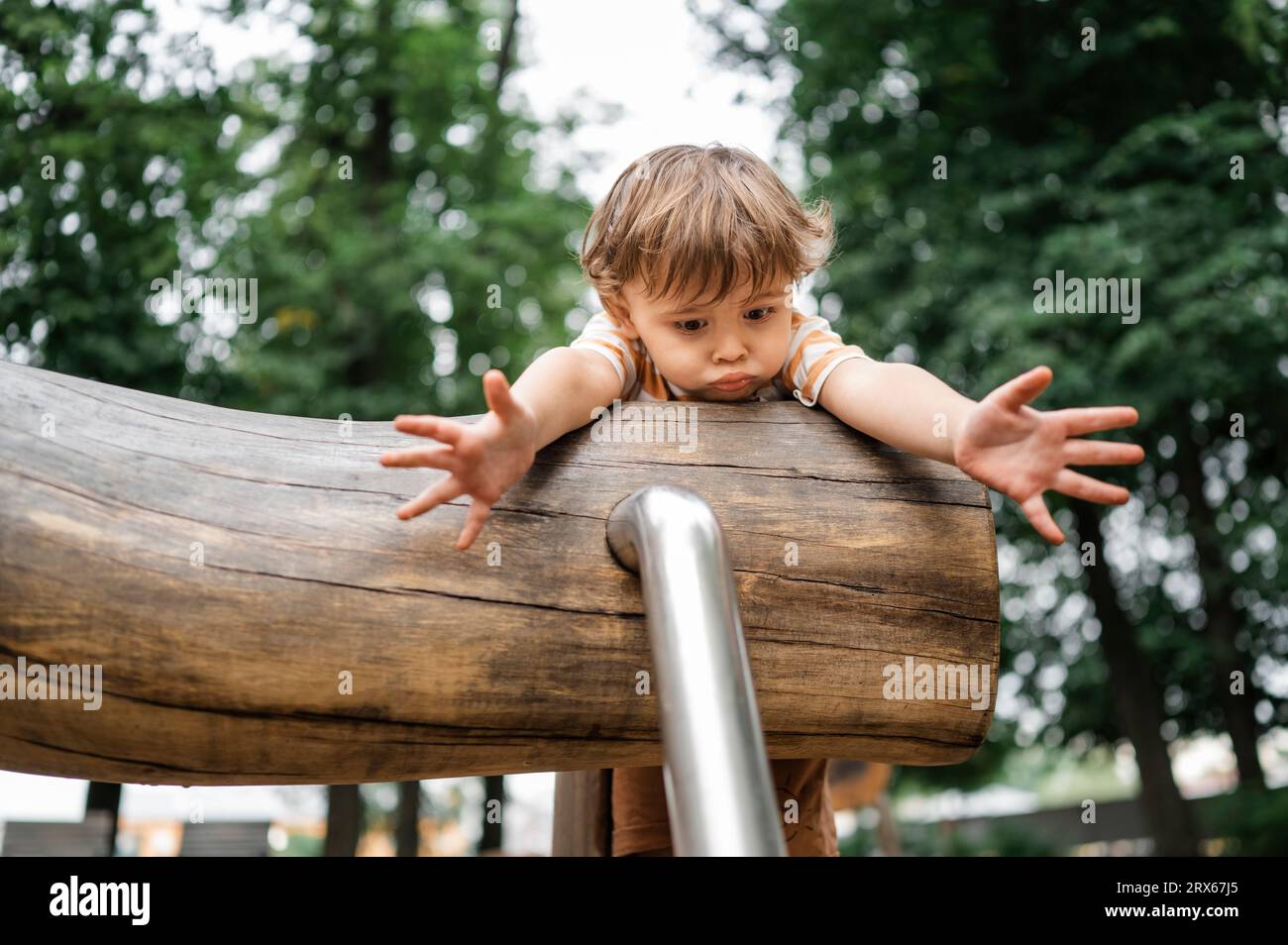 Erschrockener Junge, der im Park auf Spielgeräten im Freien spielt Stockfoto