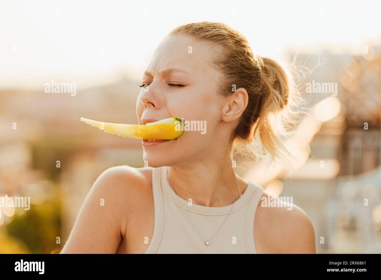 Frau, die ein Stück gelbe Wassermelone in den Zähnen hält Stockfoto