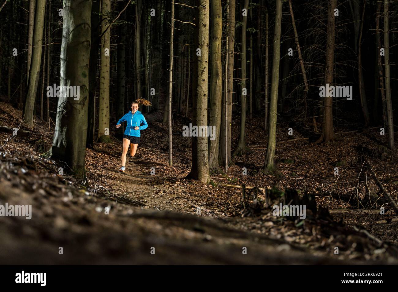Entschlossene junge Sportlerin beim Joggen inmitten von Bäumen im Wald Stockfoto