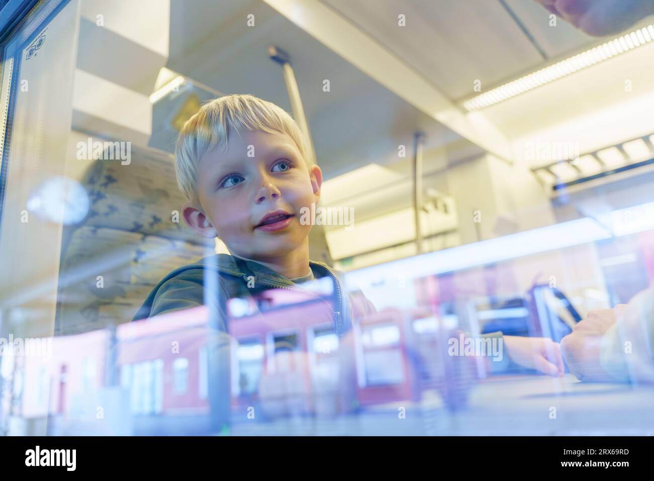 Lächelnder Junge, der durch das Zugfenster schaut Stockfoto