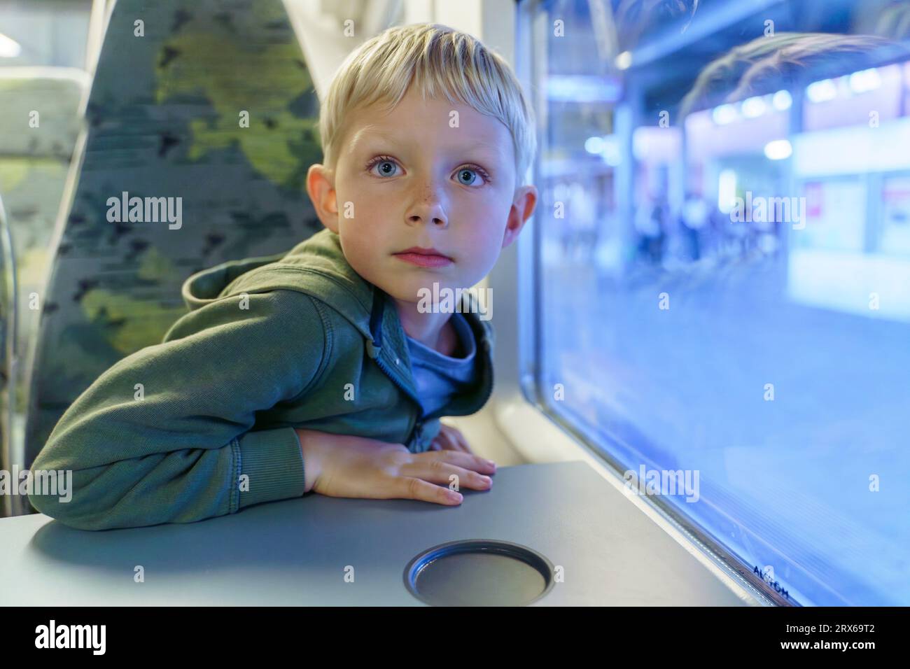 Blonder Junge sitzt im Zug in der Nähe des Fensters Stockfoto