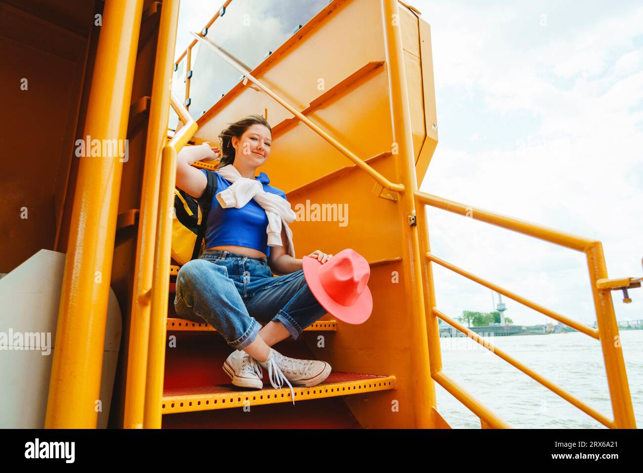 Teenager-Mädchen, das auf der Treppe der Flussfähre sitzt Stockfoto