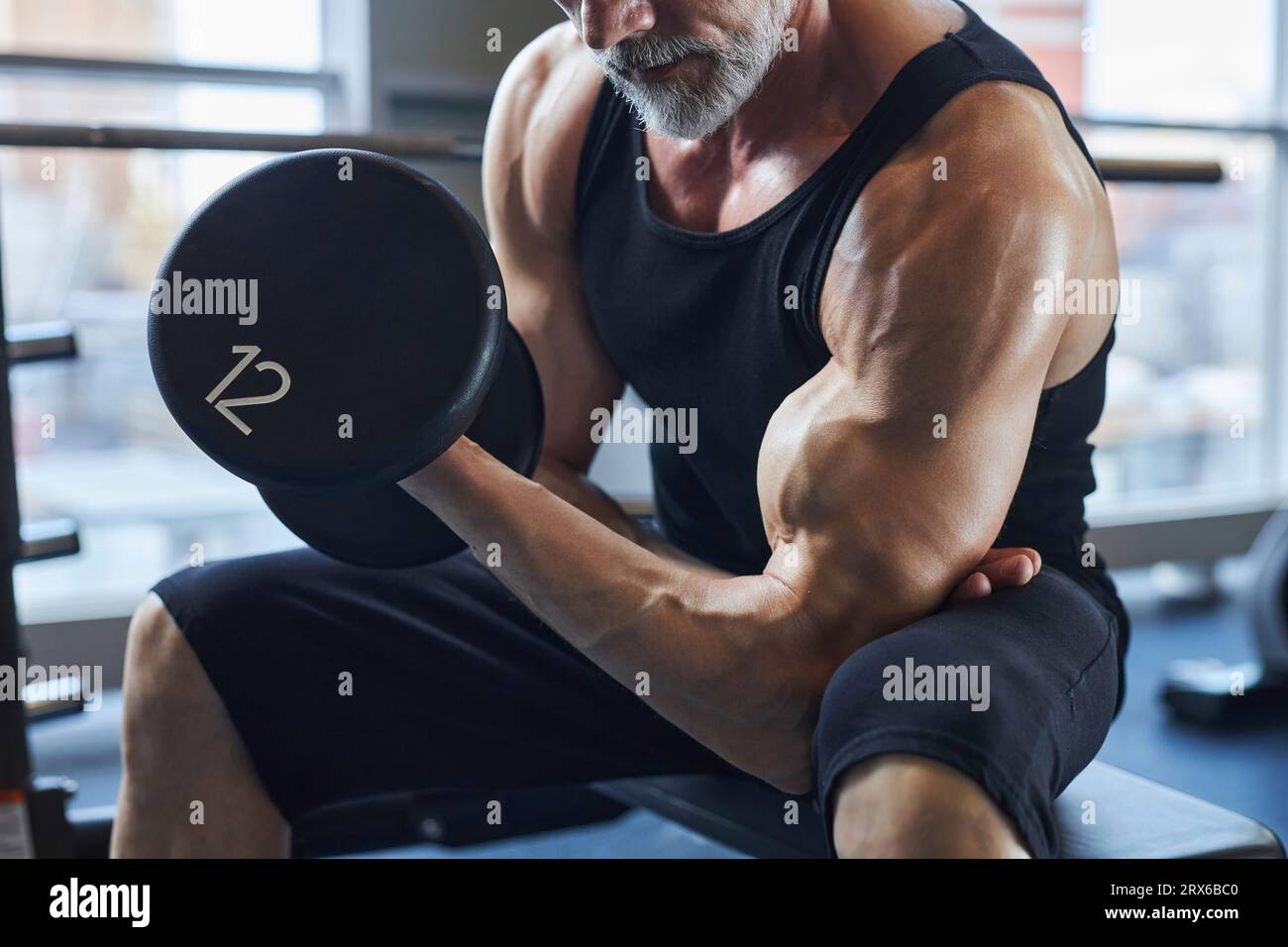 Mann mit Kurzhantel-stärkendem Bizeps im Fitnessstudio Stockfoto