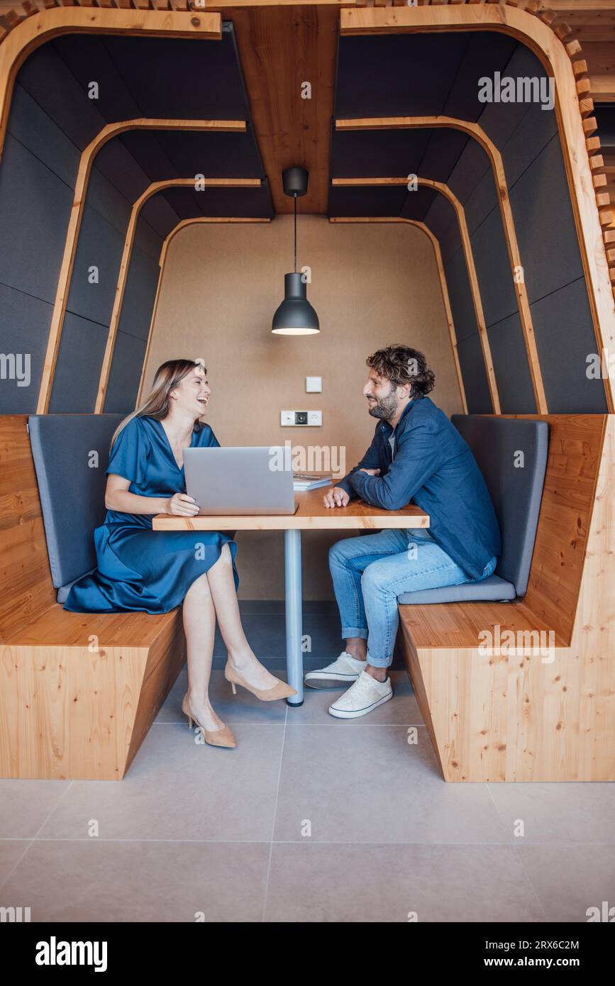 Geschäftsleute sitzen mit Laptop und lachen in der Bürokabine Stockfoto