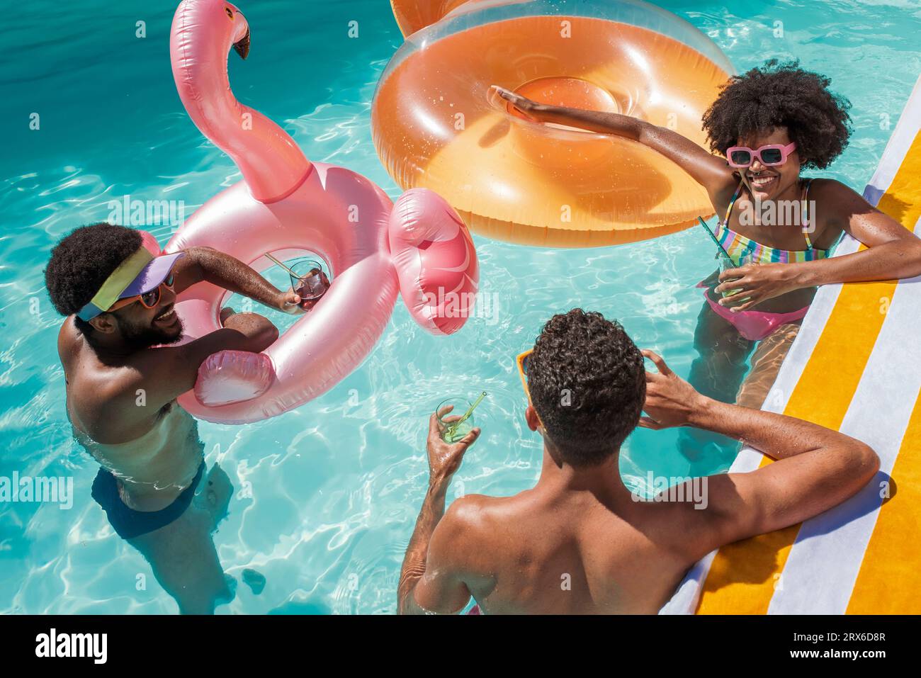 Glückliche Freunde mit aufblasbaren Schwimmern, die im Pool genießen Stockfoto