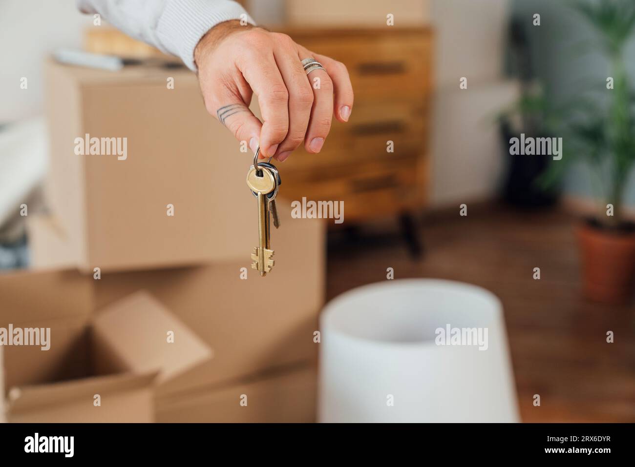 Hände eines jungen Mannes, der Hausschlüssel hält Stockfoto