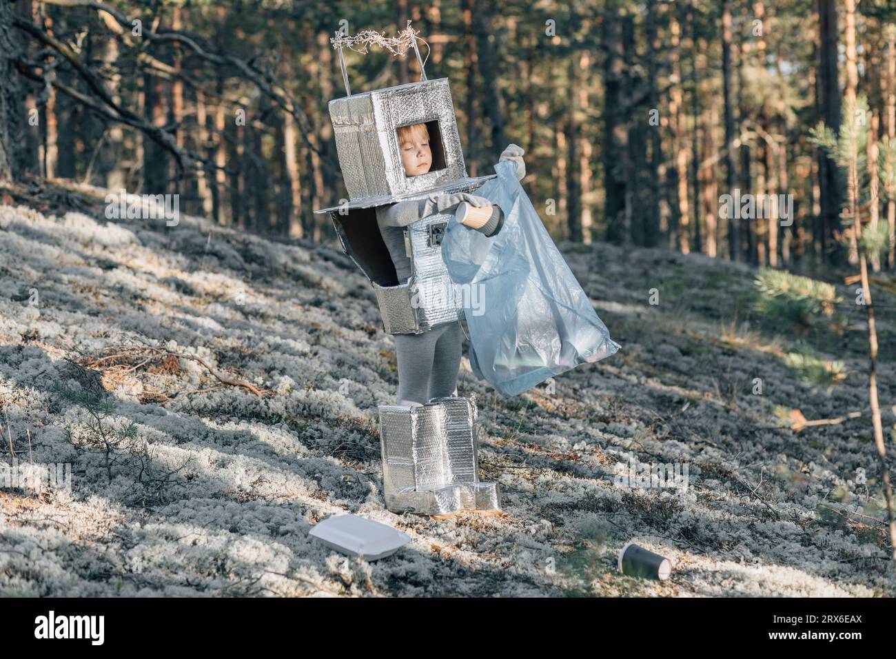 Junge im Astronautenkostüm reinigt Müll im Wald Stockfoto