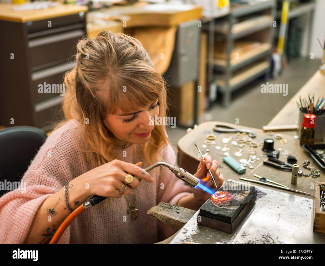 Lächelnder Handwerker, der in der Werkstatt einen Goldring verschweißt Stockfoto