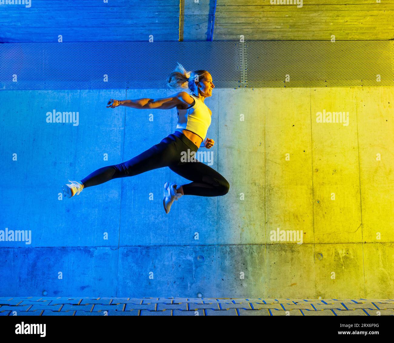 Frau springt vor einer neonfarbenen Wand Stockfoto