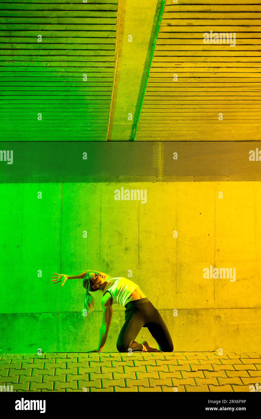 Aktive Frau, die vor einer farbigen Wand trainiert Stockfoto